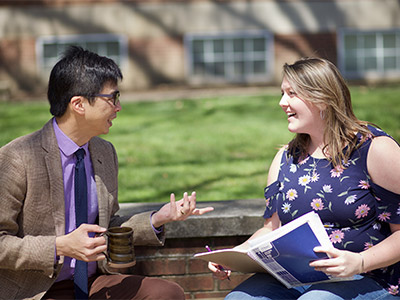 Professor Ken Woo and student talking in courtyard