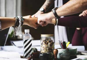 four hands meet in a fist bump over a table, coming in at different angles